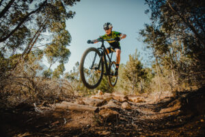 Wide angle view of a mountain biker speeding downhill on a mountain bike track in the woods