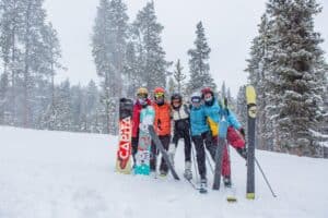 group holding skis and snowboards up on slopes